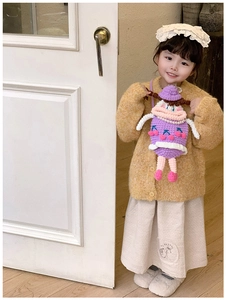 Kid modeling a purple knitted doll crossbody bag with pearl necklace and cherry details