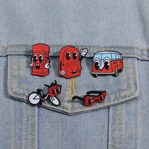 Close-up of five red cartoon enamel pins with cute eyes on a blue denim jacket pocket