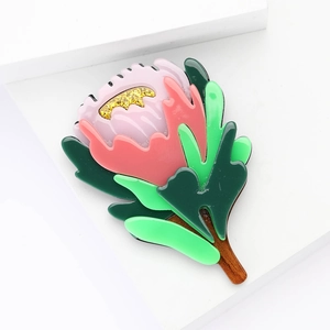 Elegant acrylic protea flower brooch in pink and red with green leaves on white background