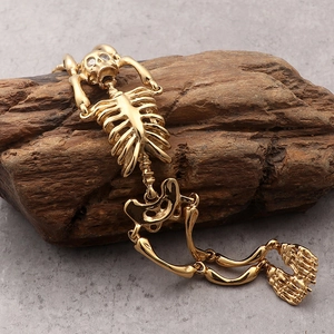 Detailed macro view of a gold-plated gothic skeleton bone bracelet on a rustic wood surface