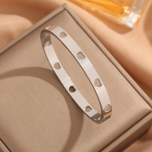 Elegant silver stainless steel bangle with hollow heart patterns on a jewelry box