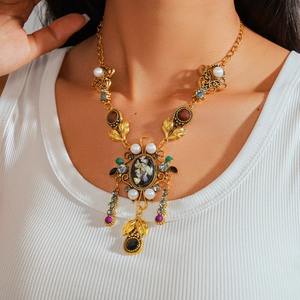 Detail of vintage gold necklace with resin pearls and colorful gemstones on a model