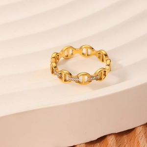Gold chain link ring with white zircon micro-inlays on textured stone display