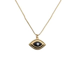 Close-up of gold-plated evil eye pendant necklace with white and black enamel detail