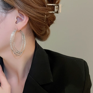 Detailed texture of layered silver circle hoop earrings worn on a model's side profile