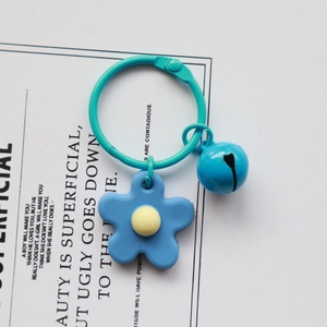 Detailed macro view of a cute blue flower keychain with a small matching bell charm