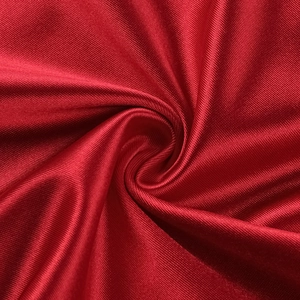 Close-up of deep red satin fabric with elegant silk texture and flowing drapes