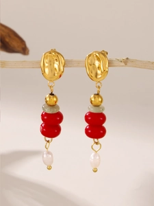 Detail of gold circular earrings with red beads and natural freshwater pearl tassels