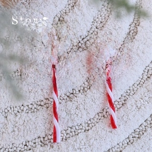 Close-up of red and white spiral lollipop Christmas ornaments on white plush background