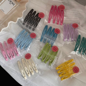 Colorful matte drop-shaped metal hair clips in various candy colors on white fabric
