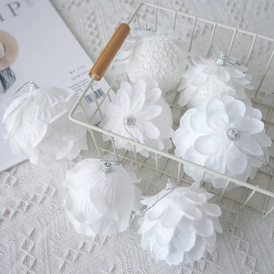 White petal-shaped Christmas foam ornaments with glitter in a white wire basket