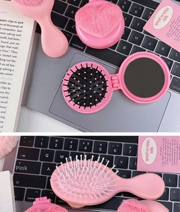 Pink heart plush puff and portable folding hairbrush set on a laptop keyboard