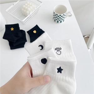 Detail of embroidered white and black cotton socks with moon, heart, and star patterns