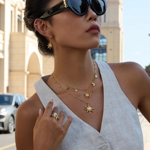 Detailed view of gold sun moon star jewelry set featuring pearls on a model outdoors