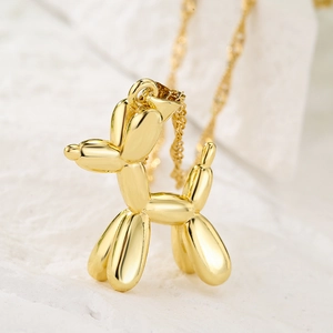 Minimalist 18K gold plated balloon dog pendant necklace on textured stone background