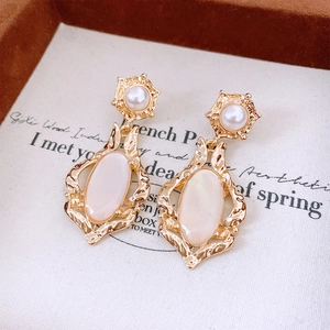 Detail of vintage French style gold earrings with shell-like oval stone and pearl accent