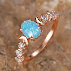 Macro shot of rose gold star and moon ring with oval blue opal and zircon accents