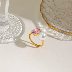 Detail of pink oval zircon and white pearl set on a gold adjustable stainless steel ring