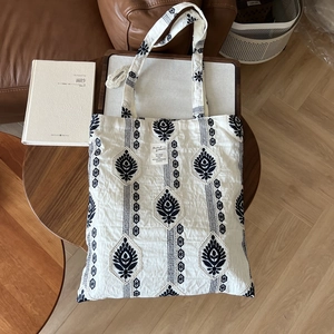 Detailed embroidery of black bohemian geometric patterns on white linen tote bag