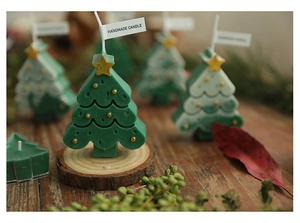 Detail of handmade green Christmas tree candle with gold stars on a rustic wood base