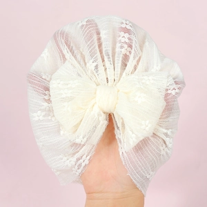 White floral lace baby turban hat with a large bow decoration for newborns and infants