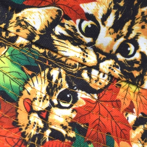 Close-up of cat and maple leaf print fabric with detailed parallel yellow stitching