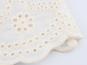 Détail de tissu en coton blanc avec broderie florale et bords festonnés