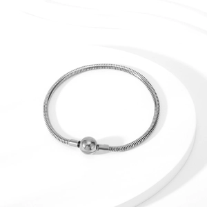 Close-up of silver snake bone bracelet with a round clasp on a minimalist display stand