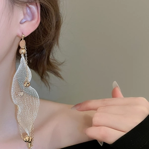 Detailed close-up of golden tassel earrings with white mesh pendants on model