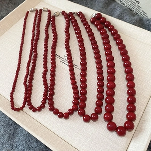 Detail view of red beaded necklaces in multiple sizes with glossy finish and lobster clasp