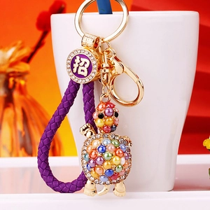 Macro detail of turtle keychain with colorful pearls and purple braided rope on white cup