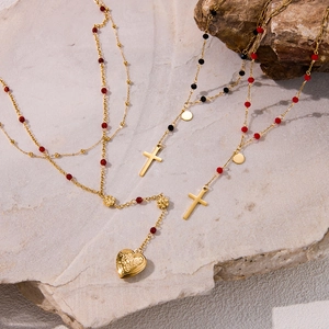 Detail of golden rosary necklaces with red beads, cross pendants, and heart locket