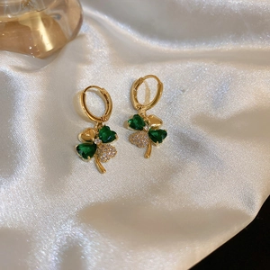 Close-up of golden clover earrings featuring green gemstones and sparkling cubic zirconia
