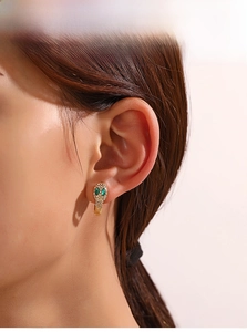 Gros plan de boucles d'oreilles serpent avec cristaux blancs et yeux vert émeraude