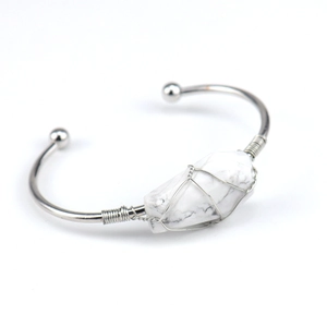 Macro detail of handmade wire wrapped white crystal stone on a metal open cuff bangle