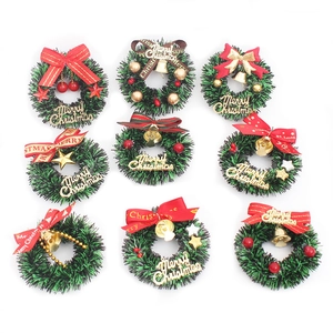 Set of nine miniature green Christmas wreaths with red ribbons and golden bells on white background