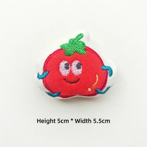 Detailed close-up of a 5cm plush red tomato brooch with green leaves and smiling face