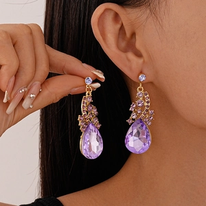 Macro detail of tear-drop purple crystal earrings with gold plating and fine engraving