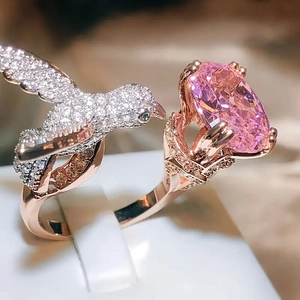Macro detail of bird-shaped ring featuring pink oval gemstone and sparkling zircon stones