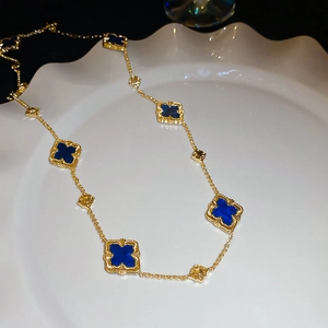 Detail view of gold-plated necklace featuring blue clover motifs with beaded edges