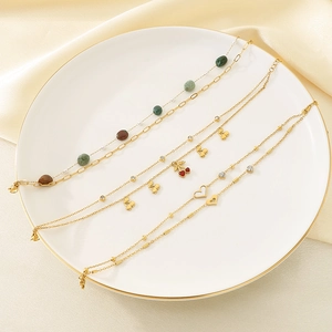 Set di cavigliere dorate con ciliegie e cuori di conchiglia con zirconi su un piatto