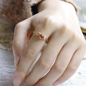 Detalle de anillo vintage bañado en oro con granate naranja y cristales blancos al dedo