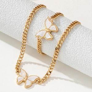Gold Cuban chain necklace and bracelet set with white butterfly pendant on white display