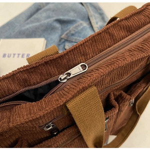 Close-up of brown corduroy bag detailing durable metal zipper and sturdy canvas handle