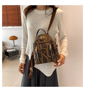 Detail of adjustable straps on a brown faux leather backpack with letter print patterns