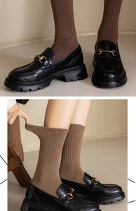 Close-up of brown ribbed socks elasticity and stylish black leather loafers outfit