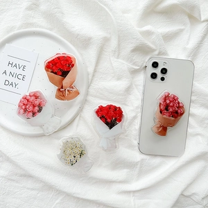 Detailed view of colorful acrylic flower phone grips on a white textured background