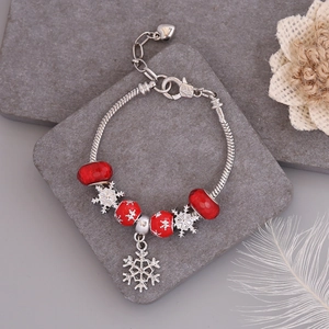 Detailed top view of Christmas snowflake charm bracelet with red glass beads on stone