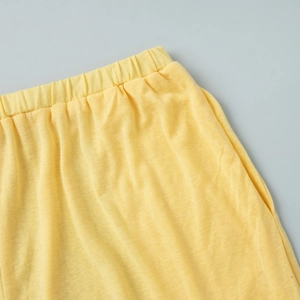 Detail of lemon yellow knit pants with elastic waistband and side pocket texture