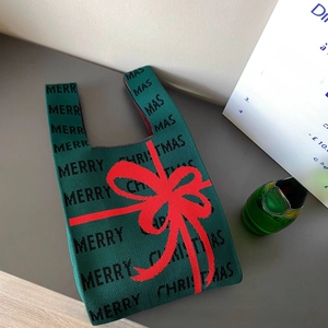 Détail d'un sac à main festif en tricot vert avec texte Merry Christmas et nœud rouge